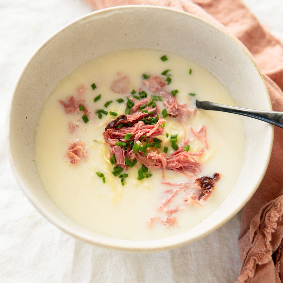 A bowl of smoked pork soup with noodles in a bowl and garnished with chives.