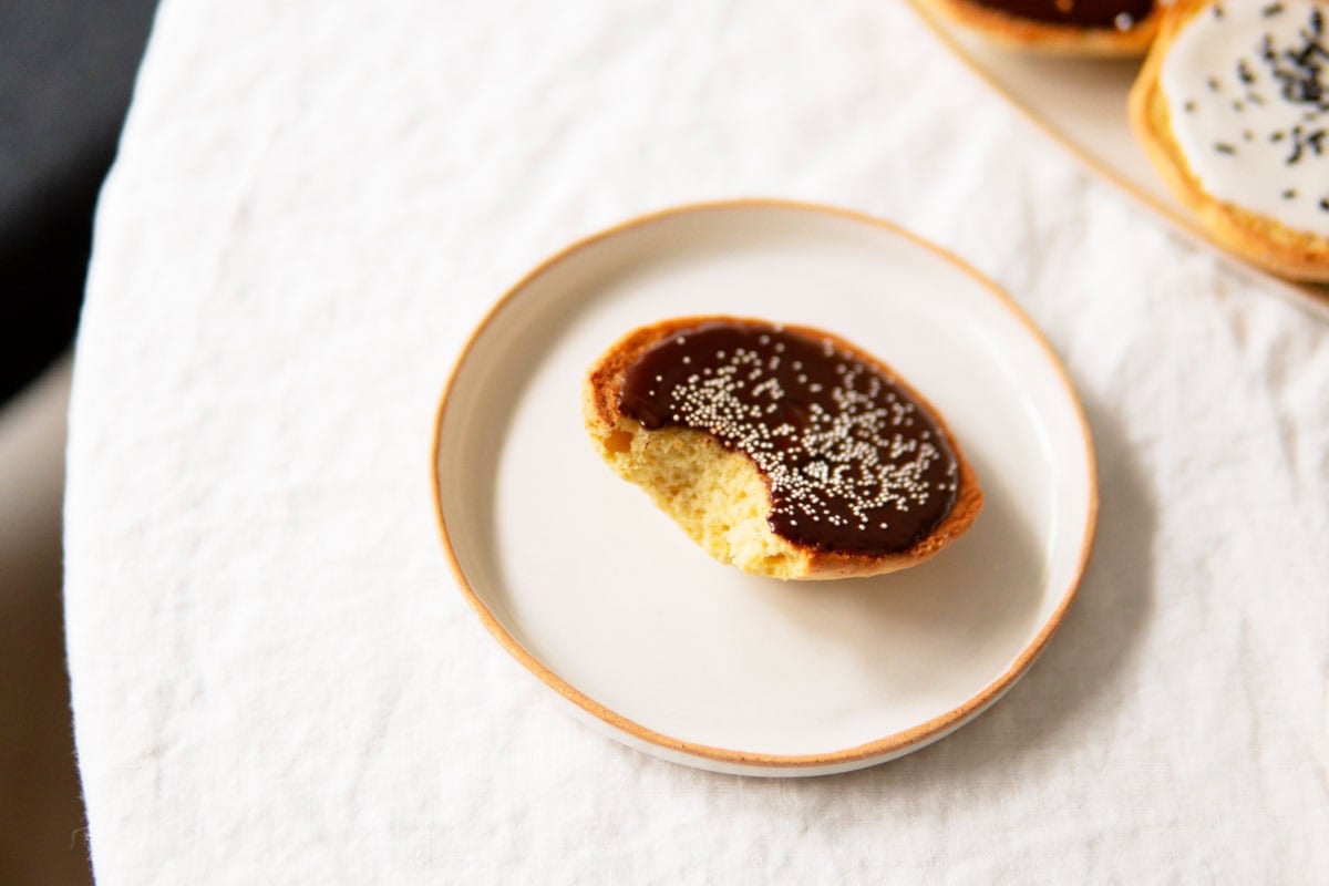 Chocolate-glazed Amerikaner with a bite taken out of it.